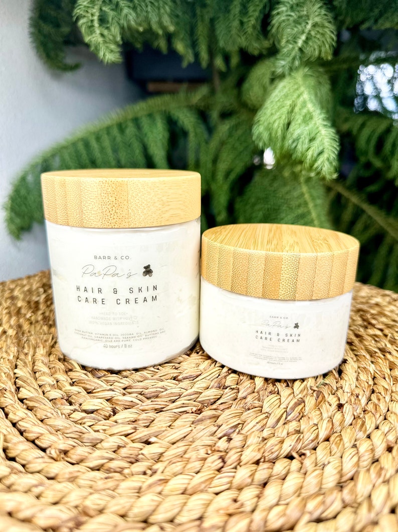 K&ouml;nnte beinhalten: Zwei Gl&auml;ser mit Haar- und Hautpflegecreme mit Bambusdeckeln. Das gr&ouml;&szlig;ere Glas ist mit "Barr & Co. PasPa's Hair & Skin Care Cream" beschriftet und das kleinere Glas mit "Barr & Co. PasPa's Hair & Skin Care Cream".