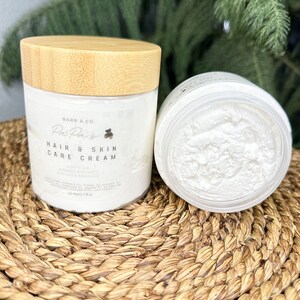 K&ouml;nnte beinhalten: Ein wei&szlig;es Glas mit Bambusdeckel, beschriftet mit "Barr & Co. Pai Pais Hair & Skin Care Cream" und einem kleinen B&auml;ren-Symbol. Das Glas ist mit einer wei&szlig;en Creme gef&uuml;llt und steht auf einer geflochtenen Matte.