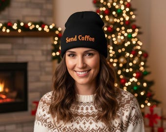 May include: A black beanie with the text "Send Coffee" in orange embroidery. The beanie is worn by a person in a patterned sweater, with a Christmas tree and fireplace in the background.