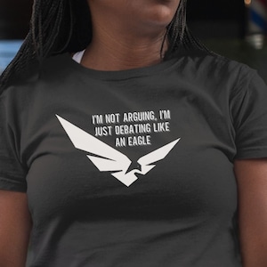 Peut inclure: T-shirt noir avec un graphique d'aigle blanc et le texte "Je ne me dispute pas, je débat comme un aigle."