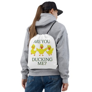 May include: White drawstring bag with the text "Are you ducking me?" and three yellow cartoon ducks.