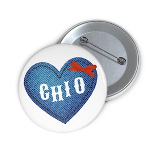 May include: A white button with a blue denim heart that says "OHIO" in white letters. The heart has a red ribbon on the top.