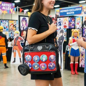 May include: Black shoulder bag with a red interior, displaying several anime character buttons. The bag has a small, heart-shaped charm and a small, round coin purse attached. The background shows anime-themed posters and cosplayers.