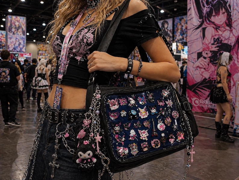 Puede incluir: Un bolso negro con un panel frontal transparente lleno de coloridos pines de estilo anime. El bolso est&aacute; adornado con cadenas y abalorios. La persona lleva un top negro con detalles en rosa, un cintur&oacute;n y un cord&oacute;n.