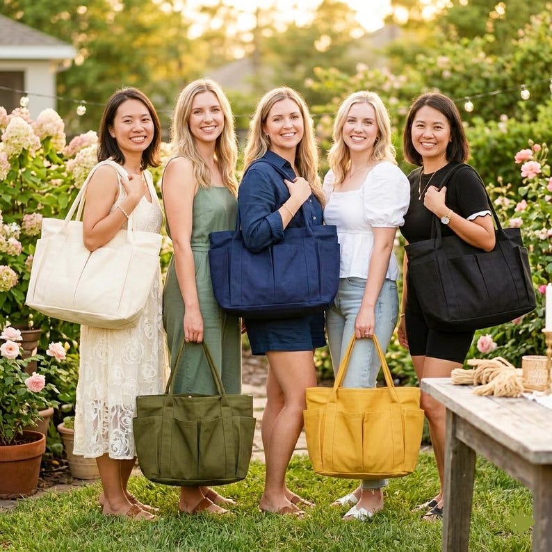 Puede incluir: Cinco mujeres posan al aire libre, cada una sosteniendo un bolso tote grande. Los bolsos son de varios colores: crema, verde oliva, azul marino, amarillo mostaza y negro. Las mujeres est&aacute;n en un jard&iacute;n con flores y vegetaci&oacute;n.