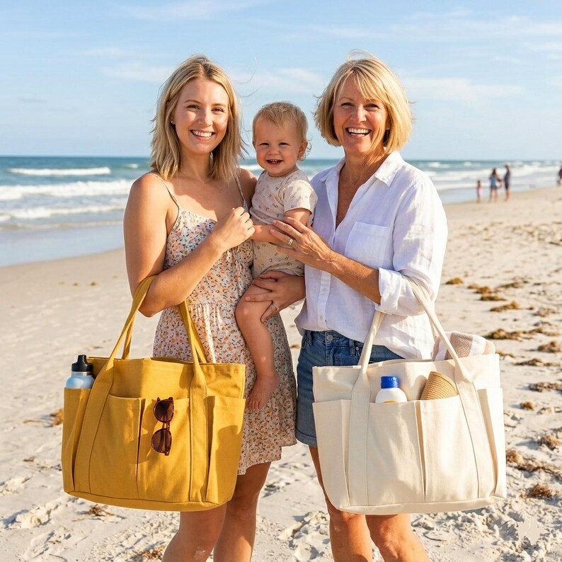 Puede incluir: Dos mujeres y un ni&ntilde;o en la playa, cada uno con un bolso tote grande. Un bolso es amarillo mostaza con m&uacute;ltiples bolsillos, gafas de sol y una botella de agua. El otro bolso es blanco roto con bolsillos, protector solar y un sombrero para el sol.