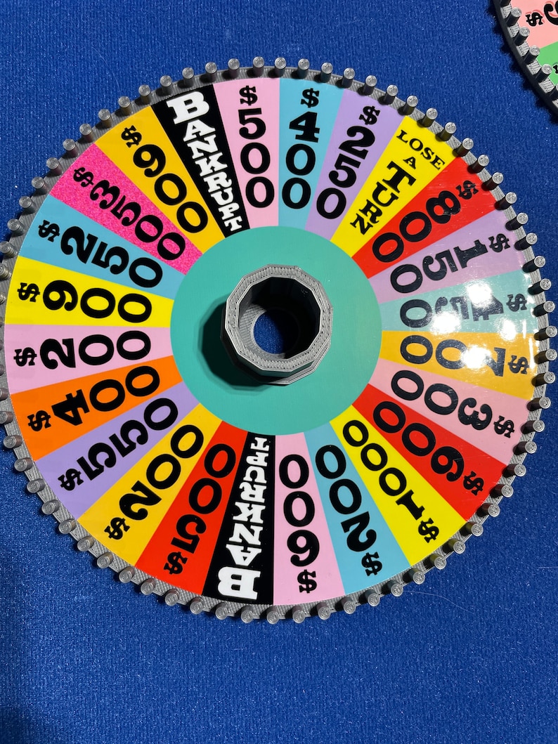 May include: A colourful wheel game with a spinning arrow. The wheel has different dollar amounts, including &pound;900, &pound;3500, &pound;250, &pound;900, &pound;200, &pound;400, &pound;550, &pound;200, &pound;500, &pound;400, &pound;250, &pound;1000, &pound;150, &pound;300, &pound;100, &pound;200, and &pound;600. The wheel also has the words "BANKRUPT" and "LOSE A TURN".