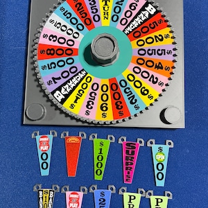 May include: A colourful wheel of fortune game with a spinning wheel and various prize options. The wheel has different dollar amounts, including $100, $200, $300, $400, $500, $600, $700, $800, $900, $1000, $1500, $2000, $2500, $3500, $5000, and "Bankrupt". There are also several smaller cards with different prize options, including "Double Play", "Jackpot", "Surprise", and "Prize".