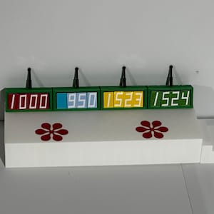 Puede incluir: Cuatro pantallas digitales verdes con números blancos sobre una plataforma blanca con calcomanías de flores rojas. Las pantallas muestran los números 1000, 950, 1523 y 1524.