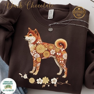 May include: Dark chocolate-coloured sweatshirt with a floral Shiba Inu design. The dog illustration is decorated with yellow, orange, and white flowers. The sweatshirt has the text "Dark Chocolate" and "Customize Me!" on it.