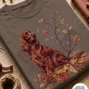 Op de afbeelding: Espresso-kleurig T-shirt met een gedetailleerde illustratie van een roodbruine Ierse Setter hond te midden van herfstbladeren en takken. De tekst "ESPRESSO" staat onderaan. Het shirt heeft een ronde hals.