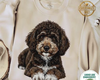 May include: A beige sweatshirt featuring a detailed illustration of a brown and white dog. The dog has fluffy fur and is lying down. The sweatshirt has a round neckline and long sleeves. The image also includes a "Customize Me!" tag.