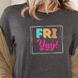 May include: A dark gray t-shirt with a white box around the text "FRI Yay!" in colorful letters.