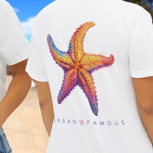 May include: White t-shirt with a pocket on the front and a colorful starfish graphic on the back. The text "URBAN FAMOUS" is printed below the graphic.