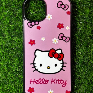 May include: A pink Hello Kitty phone case with a black border. The case features a white Hello Kitty face with a red bow, surrounded by pink bows and white and red flowers.
