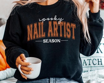 May include: Black crewneck sweatshirt with the text "spooky NAIL ARTIST SEASON" in orange and white lettering. The sweatshirt is a regular size M.