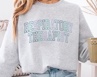 May include: A gray sweatshirt with the text "RESPIRATORY THERAPIST" in a gradient of green, purple, and blue.