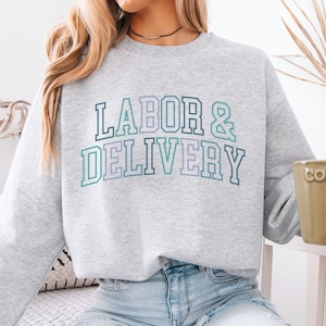 May include: A gray sweatshirt with the text "LABOR & DELIVERY" in a colorful, outlined font.