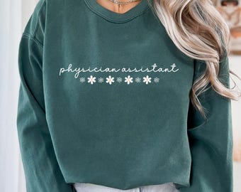 May include: A dark green sweatshirt with the text "physician assistant" in white lettering and a row of small white flowers below the text.