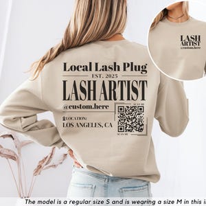 May include: A tan sweatshirt with a black print that says "Local Lash Plug Est. 2025 Lash Artist @custom.here" and a QR code. The text "Location: Los Angeles, CA" is also printed on the sweatshirt.