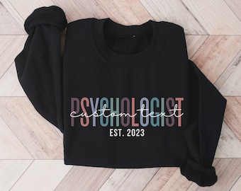 May include: Black sweatshirt with the text "PSYCHOLOGIST custom text EST. 2023" in colorful letters.
