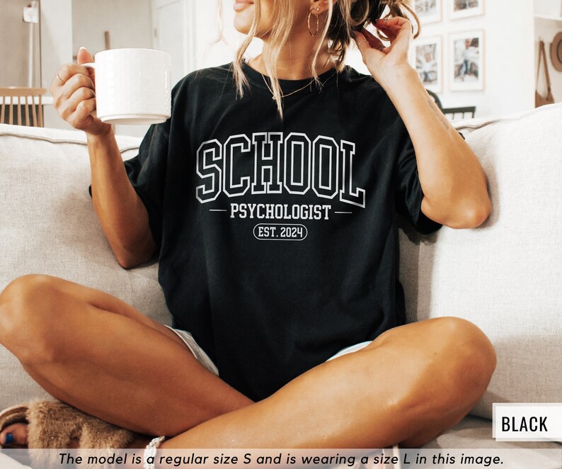 May include: Black t-shirt with white text that reads "SCHOOL PSYCHOLOGIST EST. 2024".