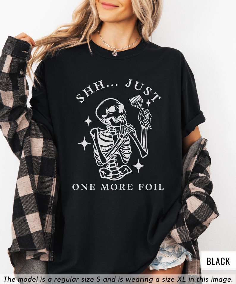 May include: Black t-shirt with a white skeleton holding a hair dye brush and the text "SHH... JUST ONE MORE FOIL".