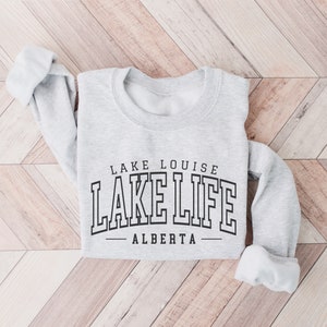 May include: Gray sweatshirt with the text "LAKE LOUISE LAKE LIFE - ALBERTA" printed on the front.