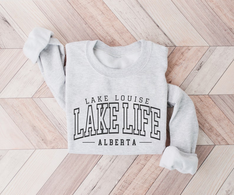 May include: Gray sweatshirt with the text "LAKE LOUISE LAKE LIFE - ALBERTA" printed on the front.