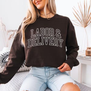 May include: A brown cropped sweatshirt with the text "LABOR & DELIVERY" in white outlined letters.
