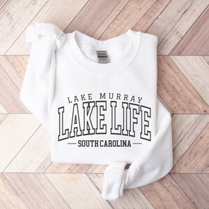 May include: White sweatshirt with black text that reads "Lake Murray Lake Life - South Carolina".