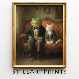 May include: Framed art print featuring a frog and a cat dressed in formal attire, seated on a red upholstered sofa. The frog wears a green jacket, bow tie, and gray pants. The cat wears a green jacket and white ruffled shirt. The print is in a gold frame.