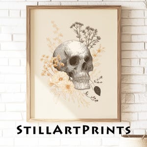 May include: Framed art print featuring a detailed grayscale illustration of a human skull surrounded by delicate floral elements in shades of cream and gold. The text "STILLARTPRINTS" is displayed at the bottom.