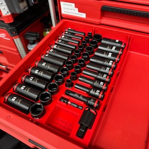 Könnte beinhalten: Eine rote Werkzeugschublade gefüllt mit schwarzen Schlagschraubern und Zubehör. Die Steckschlüssel sind in Reihen angeordnet und mit Zollgrößen beschriftet. Die Schublade ist Teil einer größeren roten Werkzeugkiste.