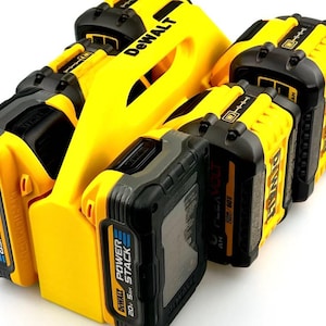 Może przedstawiać: Zestaw żółtych i czarnych akumulatorów DeWalt 20V Power Stack oraz żółta ładowarka. Baterie mają czarne i szare akcenty z logo Power Stack i specyfikacjami. Ładowarka ma logo DeWalt.