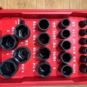 Könnte beinhalten: Eine rote Werkzeugkiste mit einem Satz schwarzer Steckschlüssel in verschiedenen Größen. Die Steckschlüssel sind in Reihen und Spalten angeordnet, mit Größen von 7,9 mm bis 38,1 mm. Die Werkzeugkiste hat einen transparenten Deckel.