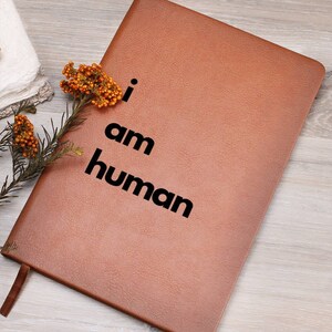 May include: A brown leather journal with the text "i am human" printed in black.