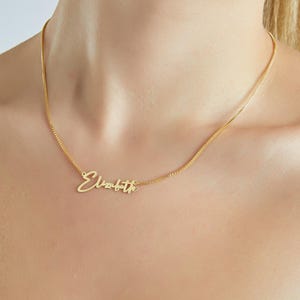 May include: A gold chain necklace with a cursive nameplate pendant that reads "Elizabeth".
