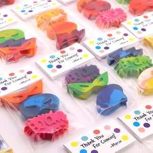 May include: Assorted colorful crayon shapes in clear plastic bags, including masks, lightning bolts, and the word "BOOM". Each bag has a small card that reads "Thank You For Coming! -Marin".