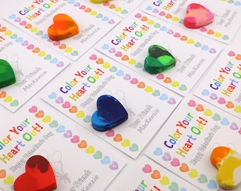 Könnte beinhalten: Herzförmige Wachsmalstifte in verschiedenen Farben liegen auf Karten mit der Aufschrift "Color Your Heart Out!" und "Happy Valentine's Day". Die Karten sind mit einem Rand aus bunten Herzen und dem Namen "Mackenzie" verziert.