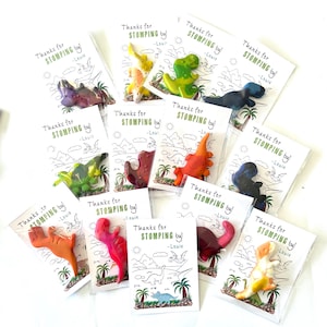 May include: Assorted dinosaur-shaped crayons in clear plastic packaging, each paired with a card that reads "Thanks for STOMPING by! -Louie." The cards feature a dinosaur-themed illustration.