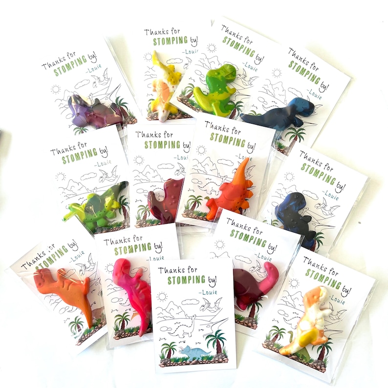 May include: Assorted dinosaur-shaped crayons in clear plastic packaging, each paired with a card that reads "Thanks for STOMPING by! -Louie." The cards feature a dinosaur-themed illustration.