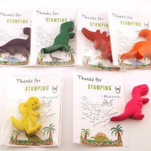 May include: Six colorful dinosaur-shaped crayons in clear cellophane bags. Each bag has a card with the text "Thanks for STOMPING by!" and a dinosaur illustration. Colors include purple, green, red, orange, yellow, and pink.