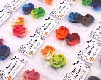 May include: Multiple clear plastic bags each containing two pumpkin-shaped wax crayons in various colors. Each bag is attached to a white card with black spiderweb illustrations, bats, and the printed text Happy Halloween! FROM: LUCAS.