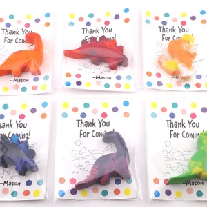 May include: Six dinosaur-shaped crayons in clear plastic bags, each on a card with colorful polka dots and the text "Thank You For Coming!" and "-Mason". The crayons are various colors, including orange, red, and green.