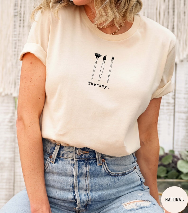 This natural t-shirt has a black image of three paintbrushes centred in the middle, with the word therapy underneath. Tailored towards people who enjoy painting also who find painting a form of therapy.
