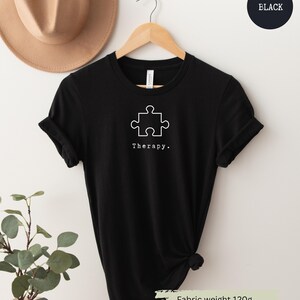 This black t-shirt has a white image of a puzzle piece centred in the middle, with the word therapy underneath. Tailored towards people who enjoy puzzles also who find puzzles a form of therapy.