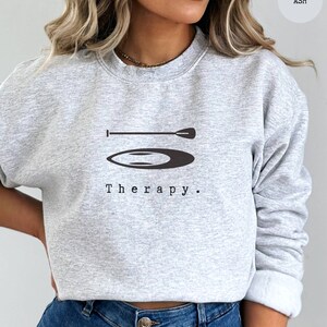 This ash sweatshirt has a black image of a sup board centred in the middle, with the word therapy underneath. Tailored towards people and couples who enjoy sup boarding also who find sup boarding a form of therapy.