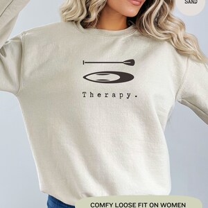 This sand sweatshirt has a black image of a sup board centred in the middle, with the word therapy underneath. Tailored towards people and couples who enjoy sup boarding also who find sup boarding a form of therapy.