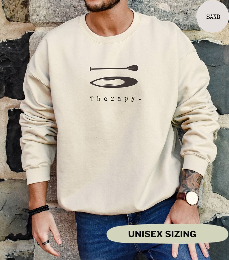 This sand sweatshirt has a black image of a sup board centred in the middle, with the word therapy underneath. Tailored towards people and couples who enjoy sup boarding also who find sup boarding a form of therapy.